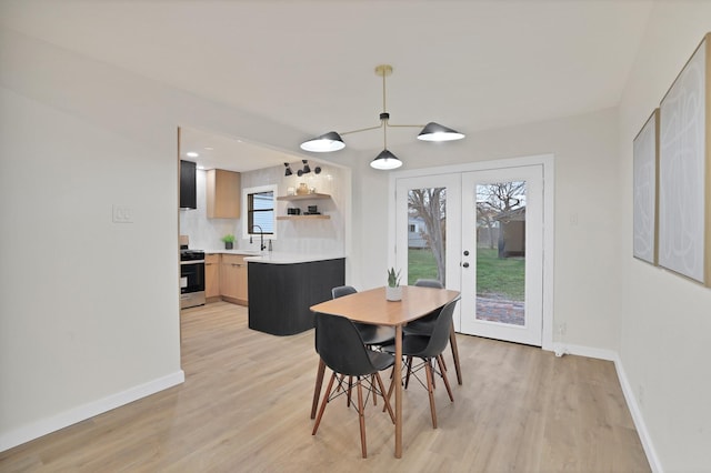 dining space featuring french doors, sink, and light hardwood / wood-style flooring