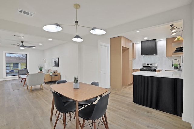 dining area with ceiling fan, sink, and light wood-type flooring