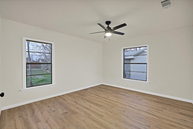 spare room with ceiling fan, a healthy amount of sunlight, and hardwood / wood-style floors