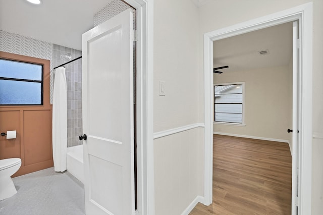 bathroom featuring toilet, ceiling fan, shower / bathtub combination with curtain, and hardwood / wood-style floors