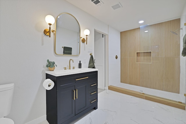 bathroom featuring a tile shower, vanity, and toilet