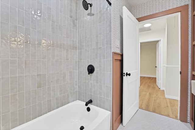 bathroom with hardwood / wood-style floors and tiled shower / bath