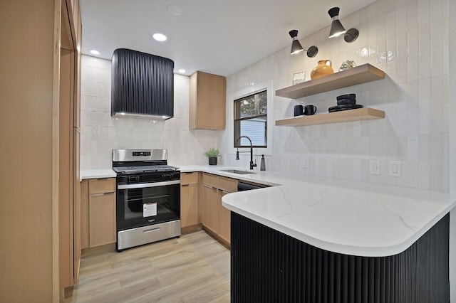 kitchen with tasteful backsplash, sink, light stone counters, kitchen peninsula, and stainless steel gas range