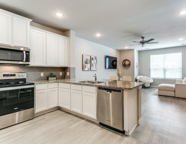 kitchen featuring white cabinetry, kitchen peninsula, appliances with stainless steel finishes, tasteful backsplash, and sink