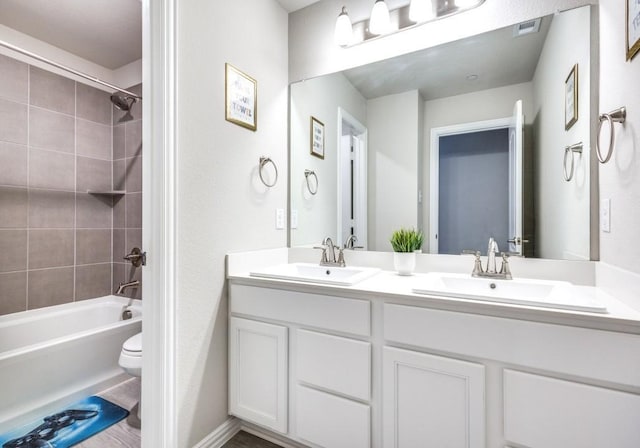 full bathroom featuring tiled shower / bath combo, vanity, and toilet