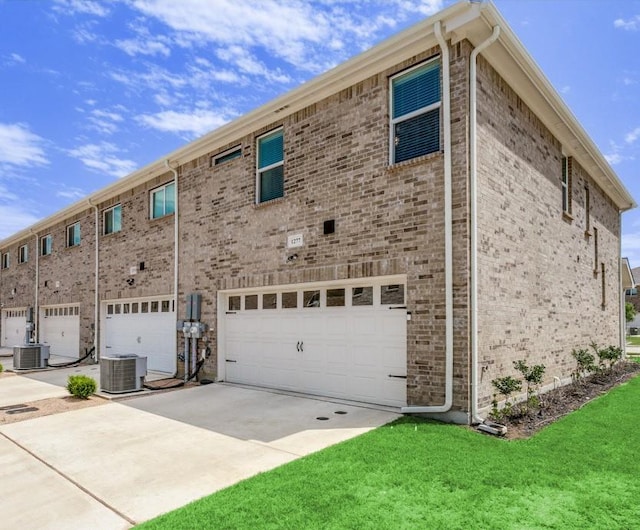 view of side of home featuring a garage, central AC, and a lawn