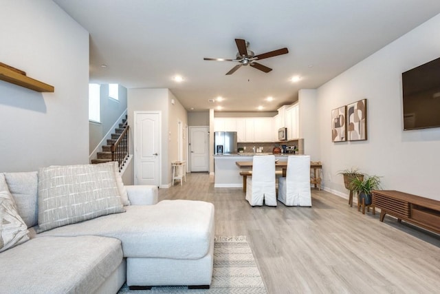 living room featuring ceiling fan and light hardwood / wood-style flooring