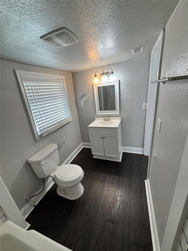 bathroom with toilet, vanity, a textured ceiling, and hardwood / wood-style flooring