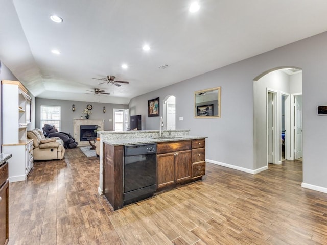 kitchen featuring black dishwasher, ceiling fan, sink, a kitchen island with sink, and hardwood / wood-style flooring