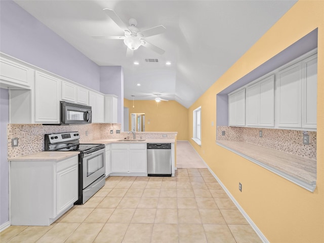 kitchen featuring light tile patterned floors, white cabinetry, appliances with stainless steel finishes, vaulted ceiling, and sink