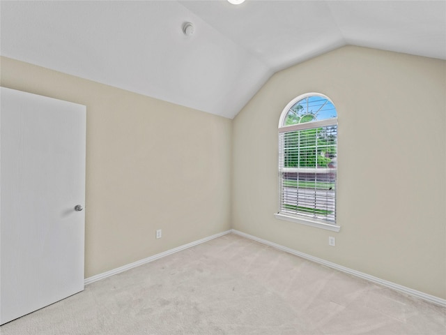 carpeted empty room featuring vaulted ceiling