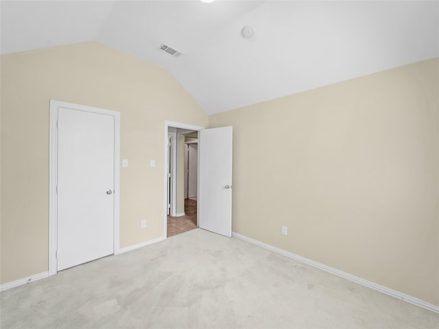 unfurnished bedroom featuring light carpet and lofted ceiling