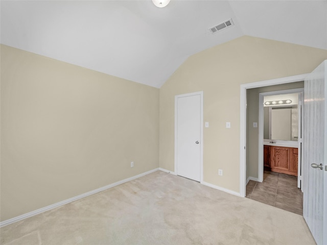 unfurnished bedroom with vaulted ceiling and light colored carpet