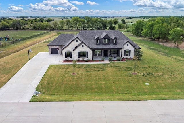 view of front facade with a front lawn, a rural view, a porch, and a garage