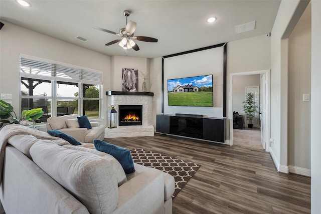 living room featuring ceiling fan, dark hardwood / wood-style flooring, and a fireplace