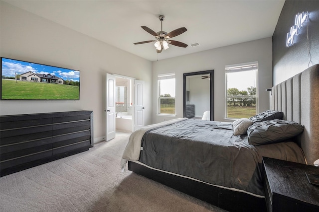 carpeted bedroom featuring ceiling fan, multiple windows, and connected bathroom