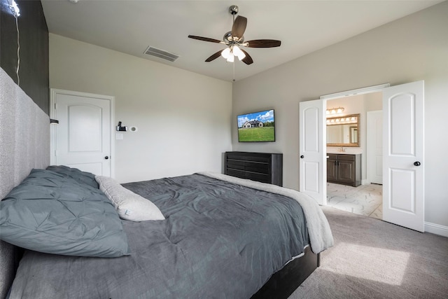 bedroom with ceiling fan, ensuite bath, and light carpet