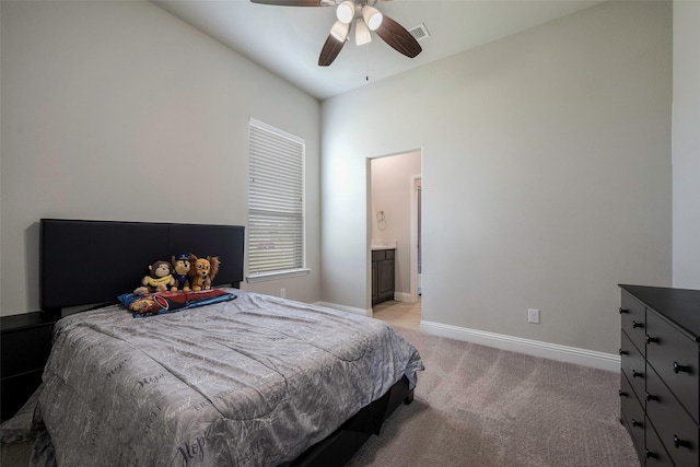 bedroom featuring ceiling fan, light colored carpet, ensuite bath, and vaulted ceiling