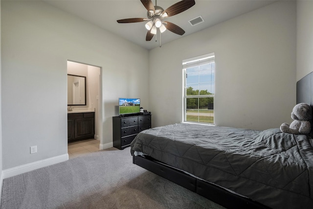 bedroom with ceiling fan, ensuite bath, and light carpet