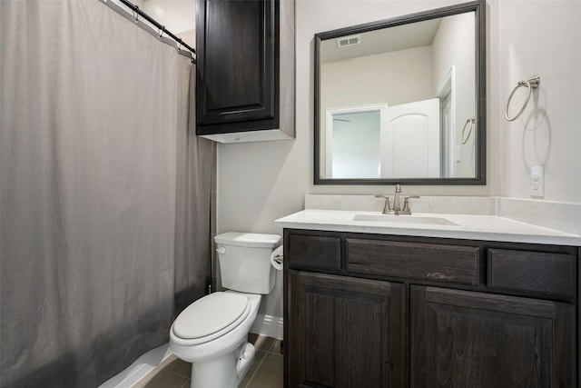 bathroom with toilet, vanity, and tile patterned flooring