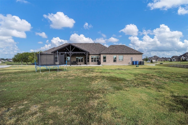 back of property featuring a trampoline, a patio area, and a lawn