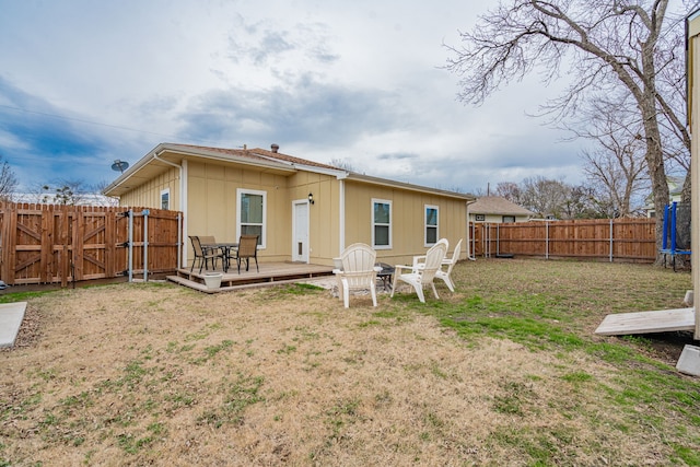 rear view of property with a wooden deck and a lawn