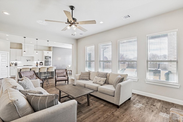 living room featuring ceiling fan and dark hardwood / wood-style floors