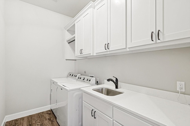 laundry room with washing machine and dryer, cabinets, dark hardwood / wood-style flooring, and sink