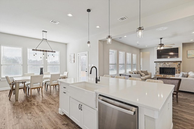 kitchen with decorative light fixtures, sink, ceiling fan, stainless steel dishwasher, and a center island with sink