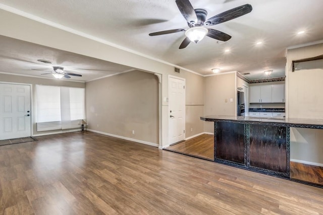 kitchen with light wood-type flooring, kitchen peninsula, crown molding, and white cabinetry