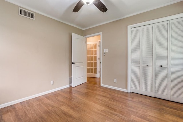 unfurnished bedroom featuring ceiling fan, ornamental molding, a closet, and light hardwood / wood-style flooring