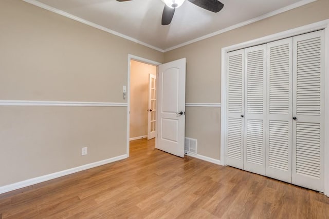 unfurnished bedroom featuring ceiling fan, a closet, light wood-type flooring, and crown molding