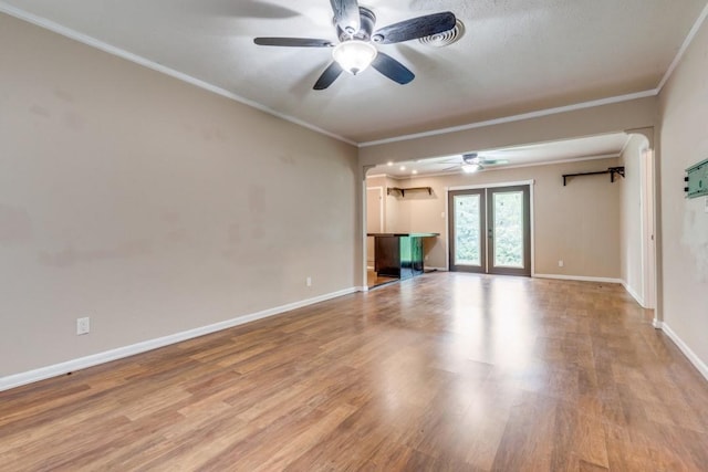 unfurnished living room with ceiling fan, crown molding, french doors, and light wood-type flooring