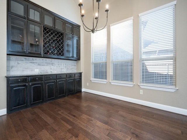 unfurnished dining area with dark hardwood / wood-style floors, lofted ceiling, and an inviting chandelier