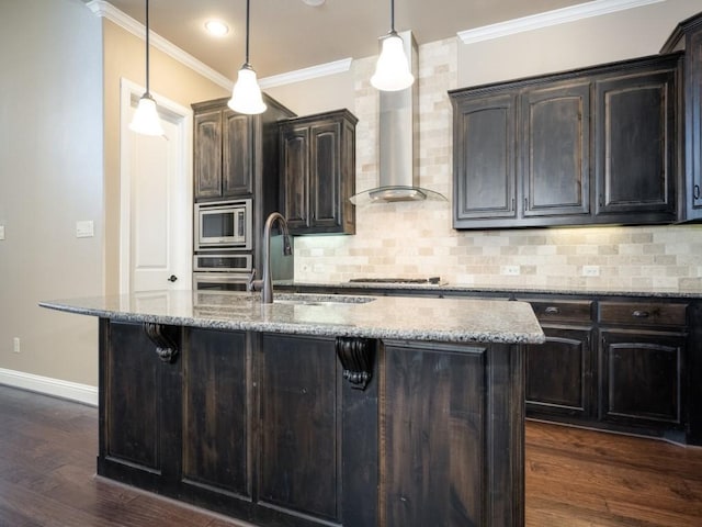 kitchen featuring light stone countertops, pendant lighting, dark brown cabinets, and a kitchen island with sink