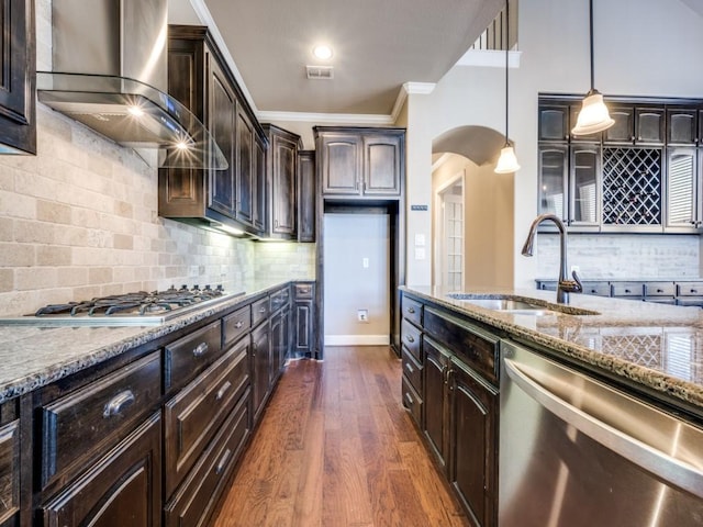 kitchen featuring pendant lighting, appliances with stainless steel finishes, wall chimney range hood, sink, and dark brown cabinets