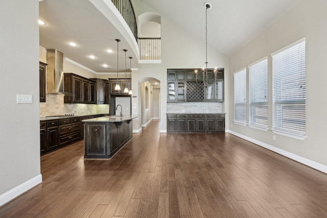 1776 Halifax St, Roanoke, TX 76262 - kitchen featuring wall chimney range hood, a sink, arched walkways, dark brown cabinets, and a chandelier