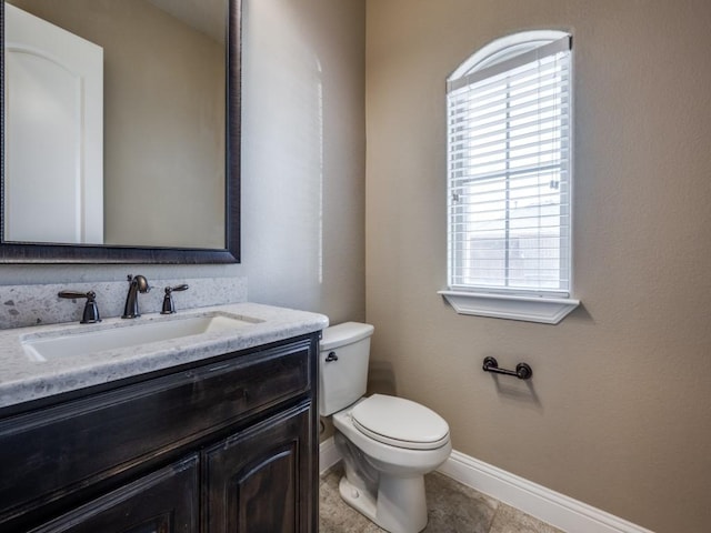 bathroom with plenty of natural light, toilet, vanity, and tile patterned flooring