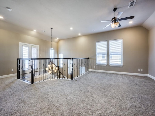 spare room featuring ceiling fan with notable chandelier, plenty of natural light, and carpet flooring