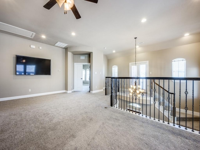 carpeted empty room featuring ceiling fan with notable chandelier