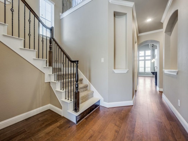 staircase with hardwood / wood-style flooring and crown molding