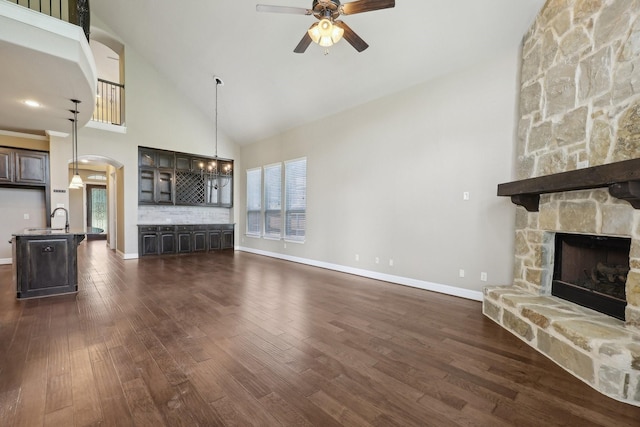 1776 Halifax St, Roanoke, TX 76262 - unfurnished living room with a ceiling fan, a fireplace, high vaulted ceiling, dark wood-type flooring, and arched walkways
