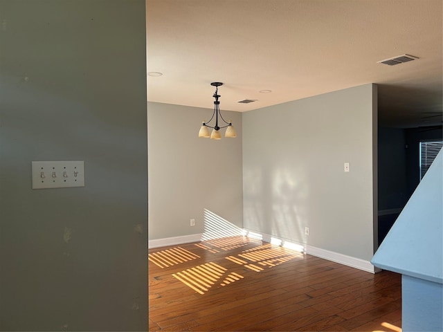 unfurnished dining area with hardwood / wood-style floors and an inviting chandelier