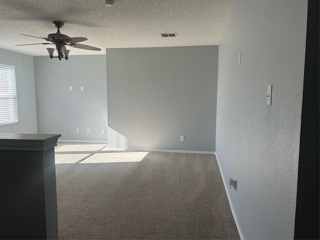 spare room featuring a textured ceiling, ceiling fan, and carpet