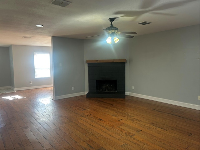 unfurnished living room featuring ceiling fan, a brick fireplace, and hardwood / wood-style flooring