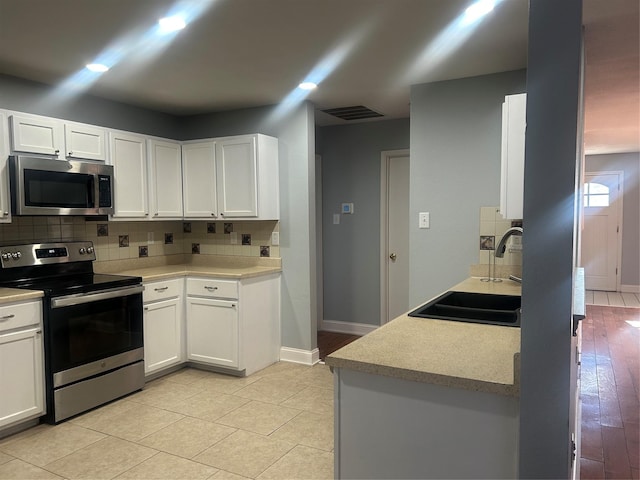 kitchen with white cabinets, appliances with stainless steel finishes, and sink