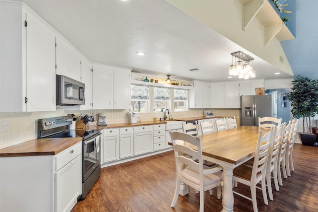 kitchen with wood counters, dark wood-style floors, visible vents, a notable chandelier, and appliances with stainless steel finishes