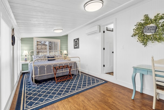 bedroom featuring an AC wall unit, baseboards, and wood finished floors