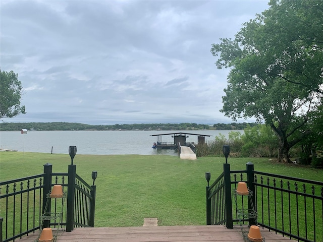 exterior space featuring a water view, a dock, and a yard