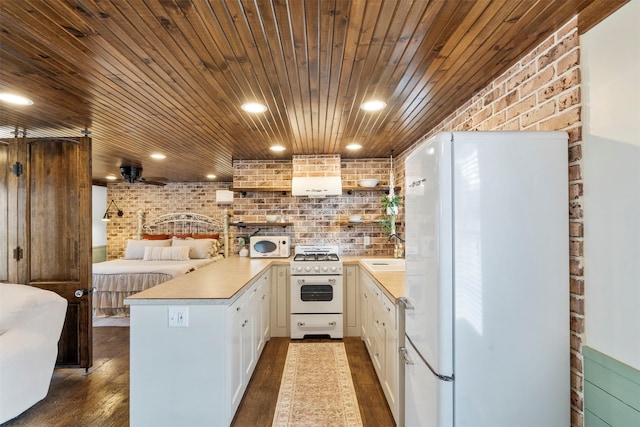 kitchen featuring white appliances, dark wood-style flooring, light countertops, and a peninsula